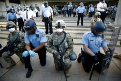 Philadelphia police and Pennsylvania National Guard take a knee at the suggestion of Philadelphia Police Deputy Commissioner Melvin Singleton, unseen, outside Philadelphia Police headquarters in Philadelphia, June 1, 2020.