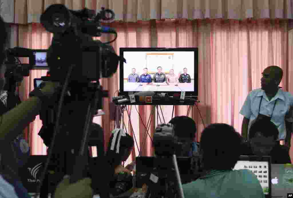 Thai journalists and foreign press watch the TV broadcast announcement of the coup by the Thai Armed Forces chiefs, at the press center of the Army Club, in Bangkok, May 22, 2014.