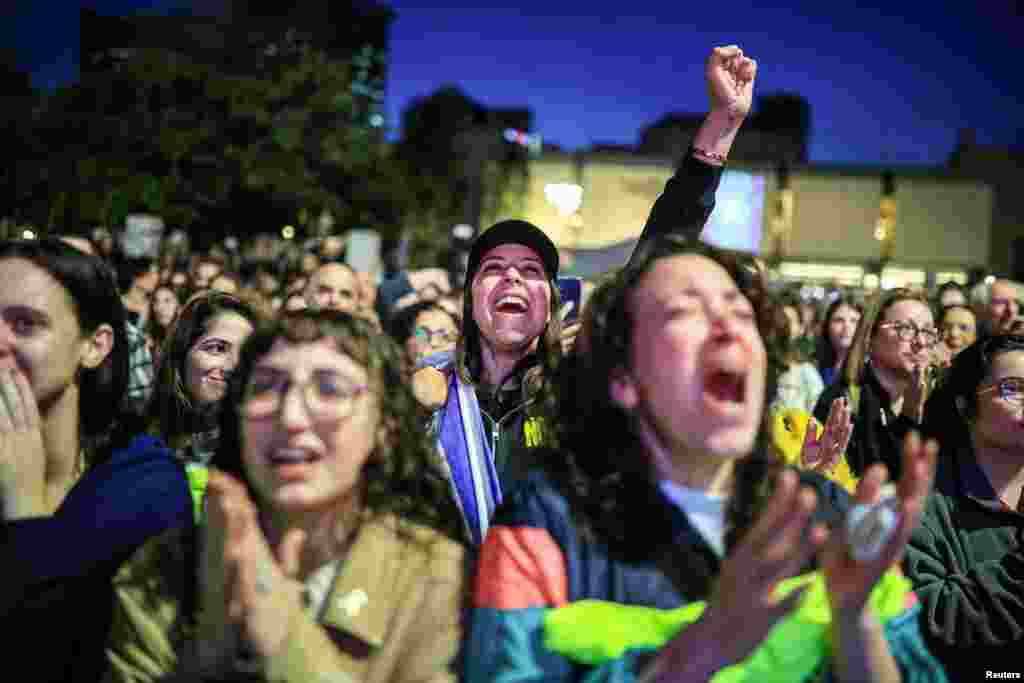 People react as they watch news coverage of the release of Romi Gonen, Doron Steinbrecher and Emily Damari, three female hostages who have been held in Gaza since the deadly October 7 2023 attack, in Tel Aviv, Jan. 19, 2025. 