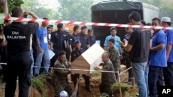 Malaysian officials provide Muslim burial to 21 human trafficking victims, believed to be Rohingya Muslim refugees, found in shallow graves in jungles bordering Thailand, in Kedah, Malaysia, June 22, 2015.