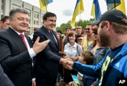 Seen during better times, Ukrainian President Petro Poroshenko, left, and then newly-appointed Odesa region governor Mikheil Saakashvili, second left, shake hands with local residents, in Odesa, Ukraine, May 30, 2015.