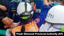 Rescuers carry a survivor from the site of a collapsed building in Preah Sihanouk province, Cambodia, June 24, 2019. 