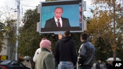 Građani prate obraćanje ruskog predsednika Vladimira Putina na ekranu na Trgu Nakimov u Sevastopolju, na Krimu