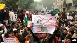 A protestor holds up a placard and sits with others in New Delhi, India, Dec. 19, 2019. 