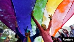 FILE - Participants dance under a a rainbow flag as they attend the sixth Delhi Queer Pride parade, an event promoting gay, lesbian, bisexual and transgender rights, in New Delhi, Nov. 24, 2013.