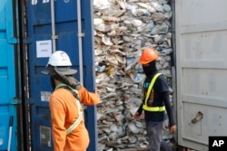 Para pekerja membuka kontainer berisi plastik yang tidak bisa didaur ulang yang ditahan otoritas pelabuhan Klang di Malaysia, 28 Mei 2019.