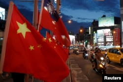 FILE - Flags of China and Taiwan flutter next to each other during a rally calling for peaceful reunification, days before the inauguration ceremony of President Tsai Ing-wen, in Taipei, Taiwan, May 14, 2016.