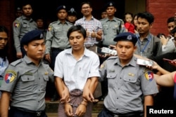FILE - Detained Reuters journalist Kyaw Soe Oo and Wa Lone are escorted by police as they leave after a court hearing in Yangon, Myanmar, Aug. 20, 2018.
