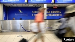 File - Passengers walk past a South African Airways (SAA) customer desk at the O.R. Tambo International Airport in Johannesburg, South Africa, Jan. 21, 2020. 