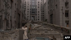 Жінка фотографує наслідки ракетної атаки на передріздвяний Київ, 20 грудня 2024р. Roman PILIPEY/AFP