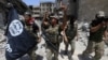 FILE - Members of the Emergency Response Division, the elite strike force of Iraq's Interior Ministry, hold an IS flag that they pulled down as they celebrate in Mosul, Iraq, July 8, 2017. Iraqi security forces continue to battle pockets of resistance across the country.