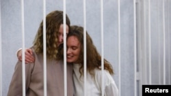 Yekaterina Andreeva and Darya Chultsova, journalists working for the Polish television channel Belsat, embrace inside a defendants' cage during a court hearing in Minsk, Belarus, Feb. 9, 2021.