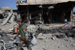 FILE - A Kurdish fighter walks past a destroyed building in the town of Sinjar on Nov. 13, 2015, after they took it from the Islamic State group in a joint operation with the coalition forces.