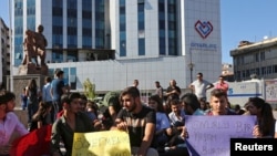 Demonstrators display signs during a protest against the suspension of teachers from classrooms over purported links with Kurdish militants in Diyarbakir, Turkey, Sept. 19, 2016.