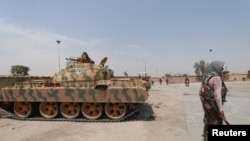 FILE - A Kurdish fighter holds his weapon as he stands near a tank in the Ghwairan neighborhood of Hasaka, Syria, Aug. 22, 2016. Recent days have seen renewed fighting between Kurdish and governments forces.