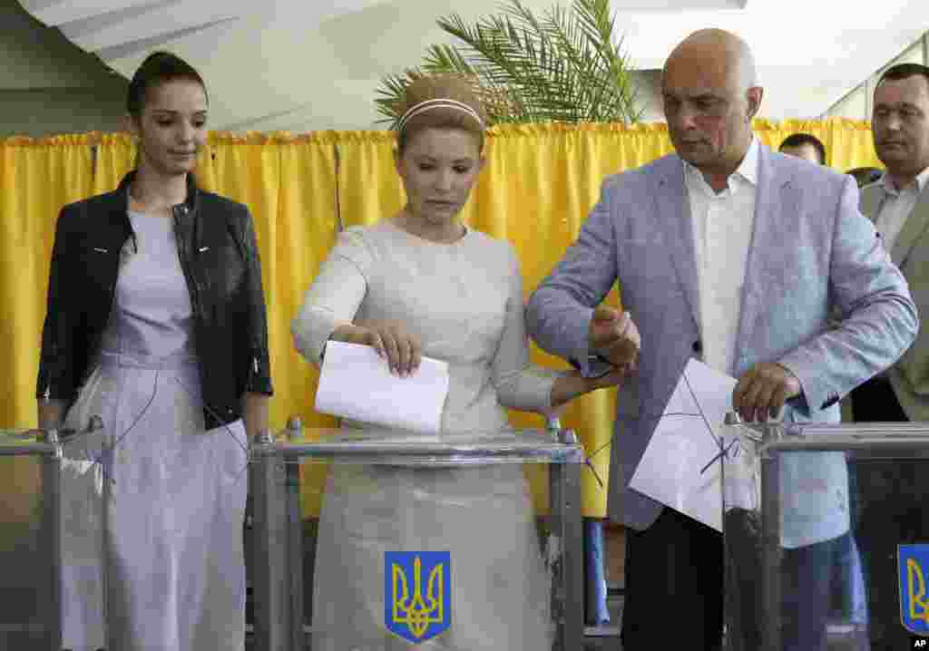 Ukraine's presidential candidate Yulia Tymoshenko casts her ballot as her husband Oleksandr, right, and daughter Yevgenia assist her at a polling station during presidential election in Dnipropetrovsk.