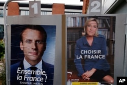 Election campaign posters for French centrist presidential candidate Emmanuel Macron and far-right candidate Marine Le Pen are posted in front of a polling station in Henin Beaumont, northern France, May 6, 2017.