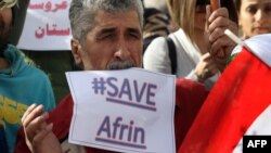 Syrian Kurds hold posters during a demonstration outside of the UN office in the northern Iraqi city of Arbil, against a military operation by the Turkish army against the Kurdish YPG forces in Syria's Afrin, Jan. 23, 2018. 