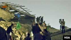 Para pendukung Moammar Gaddafi memeriksa gedung yang baru saja dibom oleh NATO di Tripoli, Libya (25/4).