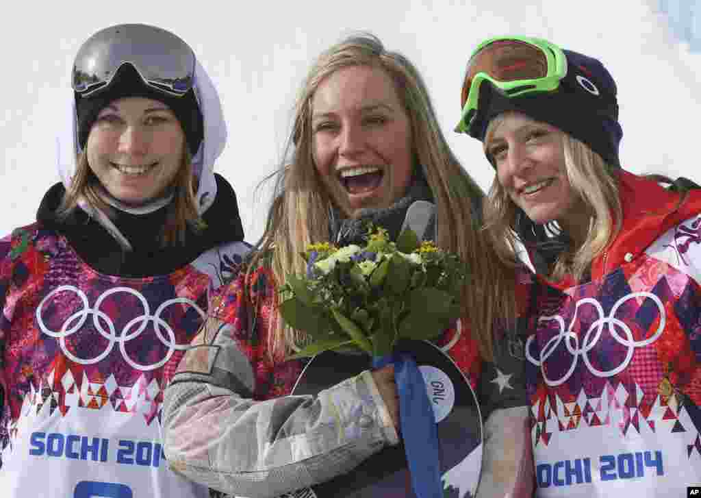 Jamie Anderson of the United States, center, celebrates with silver medalist Enni Rukajarvi of Finland, left, and bronze medalist Jenny Jones of Britain, after Anderson won gold in the women's snowboard slopestyle, Krasnaya Polyana, Russia, Feb. 9, 2014.