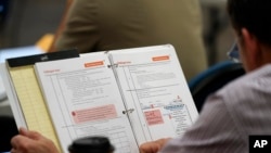 A poll worker looks over a manual during a class for Milwaukee election poll workers Saturday, Oct. 22, 2022, in Milwaukee.