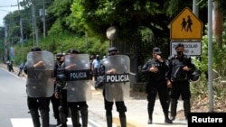 FILE - Nicaraguan police officers block journalists working outside the house of opposition leader Cristiana Chamorro after prosecutors sought her arrest, in Managua, Nicaragua, June 2, 2021.