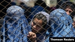 FILE PHOTO: Afghan women wait to receive free wheat donated by the Afghan government during a quarantine, amid concerns about the coronavirus disease (COVID-19) in Kabul