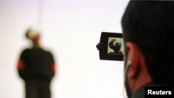 FILE - A police cameraman takes video footage of the hanging of a convicted murderer at Jamshidieh park in Tehran, Oct. 27, 2002.