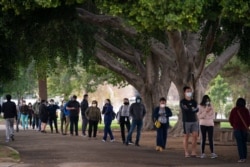 People wait in line to get their COVID-19 vaccine at a vaccination site set up in a park in the Lincoln Heights neighborhood of Los Angeles, Feb. 9, 2021.