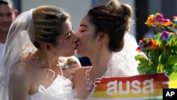 FILE - Women in wedding gowns kiss while holding a poster in support of marriage equality, during a Pride Parade in Bangkok, Thailand, June 4, 2023. A marriage equality bill sailed through both Thailand's House of Representatives and the Senate in April and June respectively.