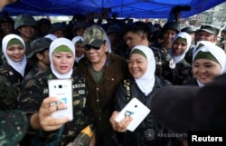 Philippine President Rodrigo Duterte, center, poses for a picture with female soldiers during his visit at Bangolo town in Marawi city, southern Philippines, Oct. 17, 2017.