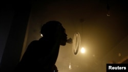 Seorang pria mengembuskan asap rokok dari rokok elektrik di toko rokok elektrik Gerobak Vapor di Jakarta, 2 Februari 2019. (Foto: Willy Kurniawan/Reuters)