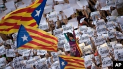 Protesters hold signs reading 'Freedom for the two Jordis' during a march to protest against the National Court's decision to imprison civil society leaders, in Barcelona, Oct. 21, 2017.