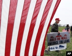 A supporter of President Donald Trump walks by during a rally for the president's visit, March 13, 2018, in San Diego. Trump on Tuesday inspected prototypes on display in California for his "big, beautiful border wall."