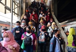 Para komuter yang mengenakan masker wajah berjalan ke peron kereta mereka di stasiun kereta Tanah Abang di Jakarta pada 18 Agustus 2020. (Foto: AFP/Adek Berry)