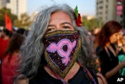 FILE - A woman takes part in an International Women's Day march in Santiago, Chile.
