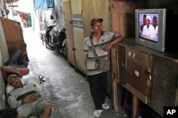 Para pekerja menyaksikan siaran langsung konferensi pers yang digelar oleh Pemimpin Front Pembela Islam (FP) Rizieq Shihab yang merencanakan unjuk rasa pada 2 Desember 2016, Jakarta, 28 November 2018.(Foto: AP)