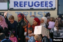 FILE - People queue to receive free food at a makeshift camp for migrants and refugees at the Greek-Macedonian border near the village of Idomeni, Greece, April 6, 2016.