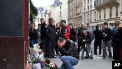 A man holds his head in his hands as he lays flowers in front of the Carillon cafe, in Paris, Nov. 14, 2015.