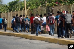 FILE - Central American migrants cross into Mexico from Guatemala, near Ciudad Hidalgo, Mexico, June 4, 2019. The migrants walked over the bridge and waited to register at a Mexican immigration office.