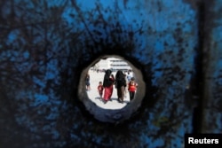 FILE - Refugee schoolchildren walk with their mothers on the first day of the new school year at one of the UNRWA schools at a Palestinian refugee camp al Wehdat, in Amman, Jordan.