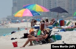 In this Sunday, Aug. 1, 2010, photo, Tracy Burgess of Cullman, Ala. sits on the beach in Orange Beach, Ala.