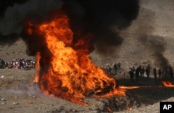 FILE - Afghan security personnel watch as flames and smoke rise after opium and narcotics are burned in a ceremony in Kabul, Afghanistan, Dec. 20, 2016.