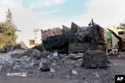 FILE - This image provided by the Syrian anti-government group Aleppo 24 news, shows damaged trucks carrying aid, in Aleppo, Syria, Sept. 20, 2016.