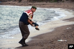 A paramilitary police officer carries the body of a migrant child after a number of migrants died and a smaller number were reported missing after boats carrying them to a Greek island of Kos capsized, near the Turkish resort of Bodrum, Sept. 2, 2015.