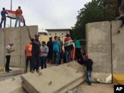 Supporters of Shiite cleric Muqtada al-Sadr walk over the blast walls surrounding Baghdad’s highly fortified Green Zone, April 30, 2016.