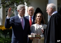 FILE - President Donald Trump watches as Supreme Court Justice Anthony Kennedy administers the judicial oath to Judge Neil Gorsuch during a re-enactment in the Rose Garden of the White House White House in Washington, April 10, 2017.