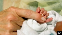 FILE: An infant grasps volunteer Kathleen Jones' hand in the neonatal intensive care unit at the University of Chicago's Comer Children's Hospital in Chicago on Wednesday, Feb. 19, 2014. Jones, 52, is one of several people who volunteer to cuddle babies at the hospital. Research 