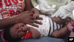 A child is vaccinated by a health worker at the Pipeline Community Health Center, situated on the outskirts of Monrovia, Liberia, on November 3, 2014. 
