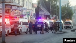 Bezbednosne snage Somalije obezbeđuju mesto eksplozije automobila bombe, dok vozila hitne pomoći čekaju kako bi se ukazala ponoć povređenima u oblasti poznatoj kao Četvrti kilometar u Mogadišu, Somalija, 31. januara 2021. (RojtersS/Feisal Omar)
